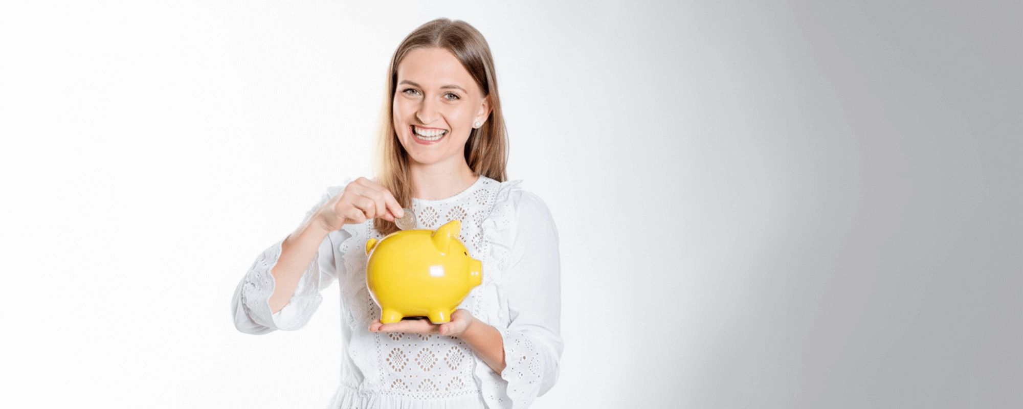 Junge Frau steckt Geld in Sparschwein.